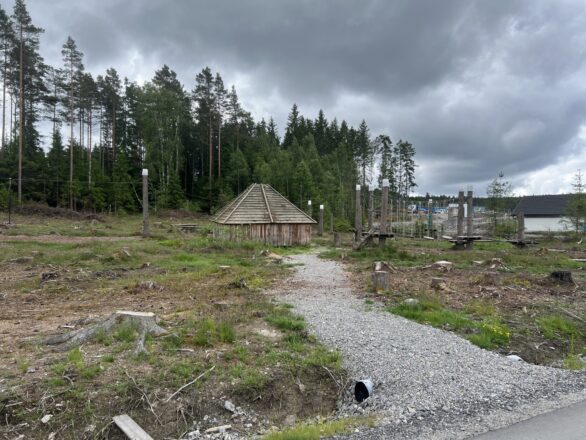 Bilde av en grillhytte inntil skogen, med en klatrebane i tre og tau ved siden av