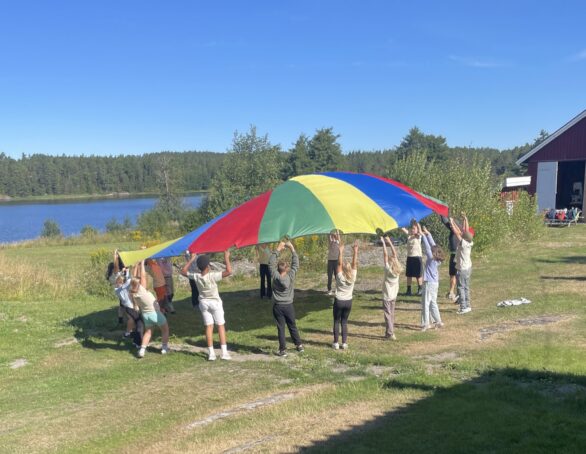 Barn som leker med en stor fallskjermduk mellom seg